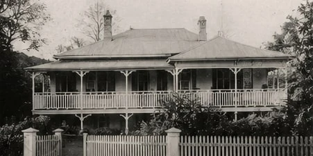 An early photograph of the homestead, its wide verandahs behind a white picket fence